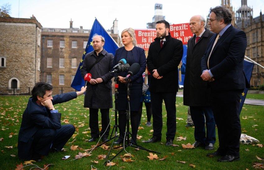 Mark Devenport holding a microphone in front of Steven Agnew, Michelle O'Neill, Colum Eastwood, Vince Cable and Stephen Farry