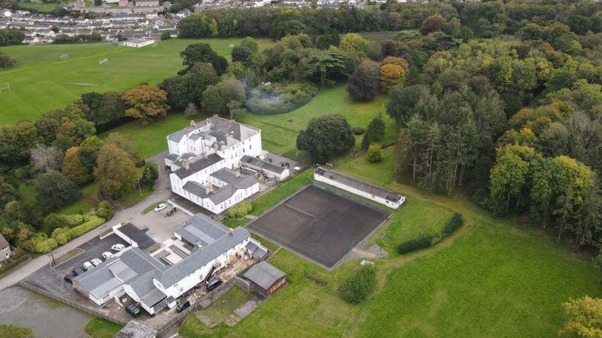 An aerial shot of Moreton House and its grounds. There is a large white building and trees surrounding it.