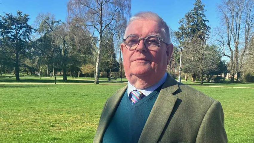 A picture of Labour candidate John Tizard with a green jumper and jacket on