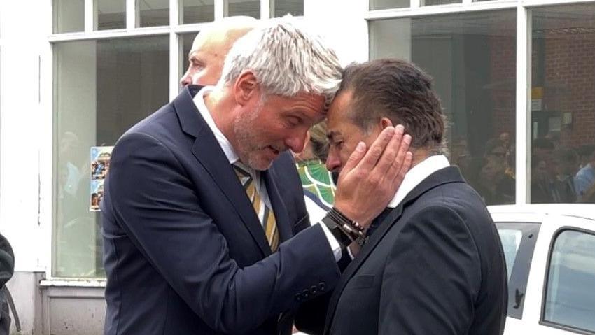 Still picture of the fathers of two of the victims of the Nottingham attacks comforting each other on the road where their loved ones were killed.