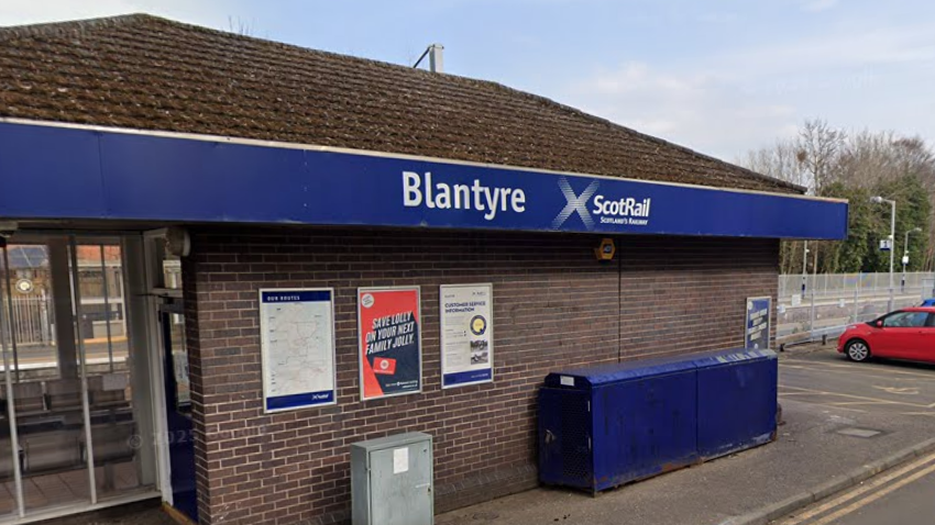 A ticket office a railway station, with a car park next to it