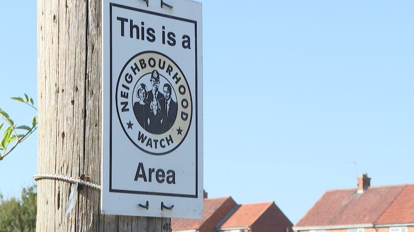 A neighbourhood watch sign strapped to a wooden post