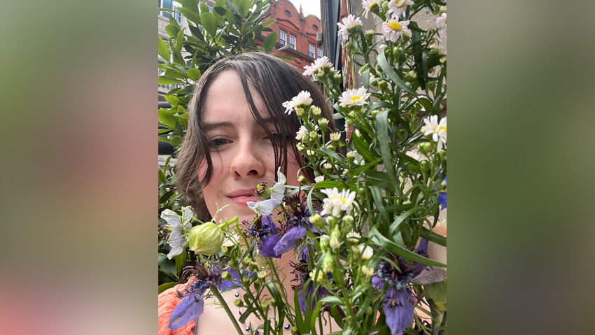 Woman photographed behind colourful flowers