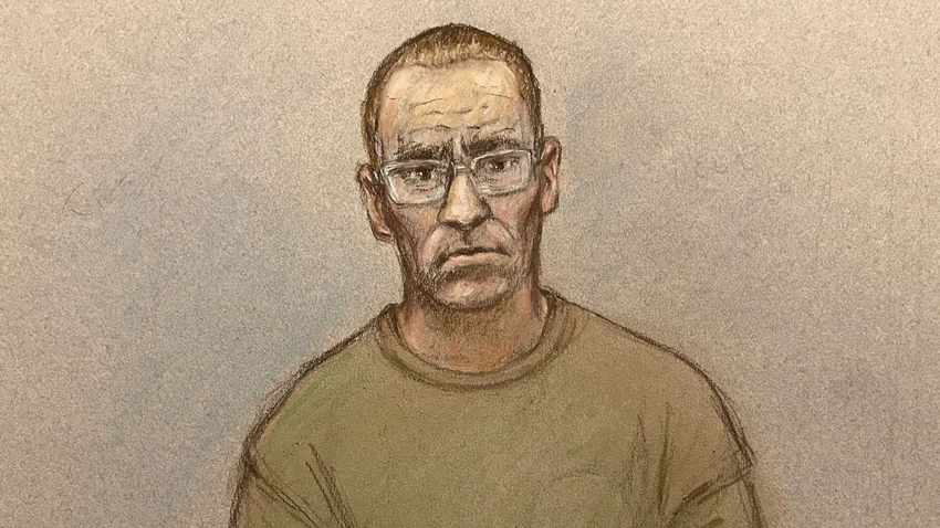 A court sketch of Paul Doyle with short hair, wearing a khaki green t-shirt and glasses, appearing via a video screen