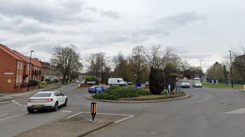 Cars and vans drive around a roundabout in York