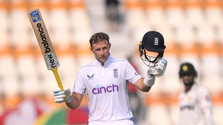 Joe Root holds his bat and helmet aloft in celebration