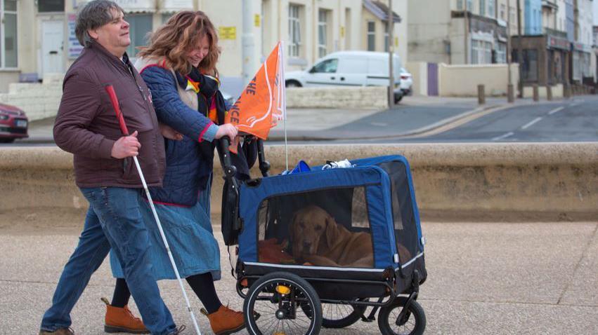 Mark Fielding, Gemma Fairhurst and Ian in his doggy pram walking along Blackpool Promenade.