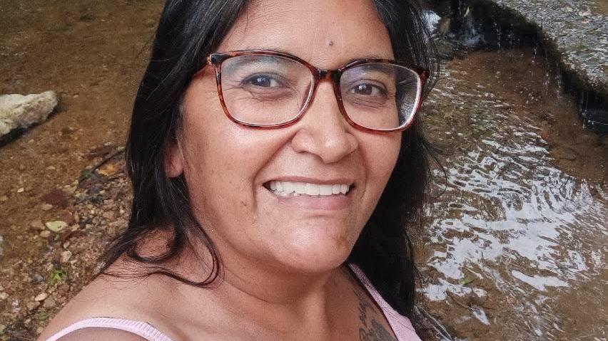 Reyna Gillahan, who died in a munitions factory explosion, tanks a selfie in a pink tank top and glasses in front of a small waterfall.
