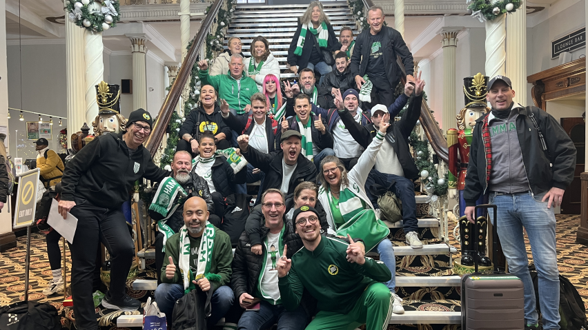 Hammarby fans smile as they pose for a big group photograph on the stairs of their hotel in Manchester.