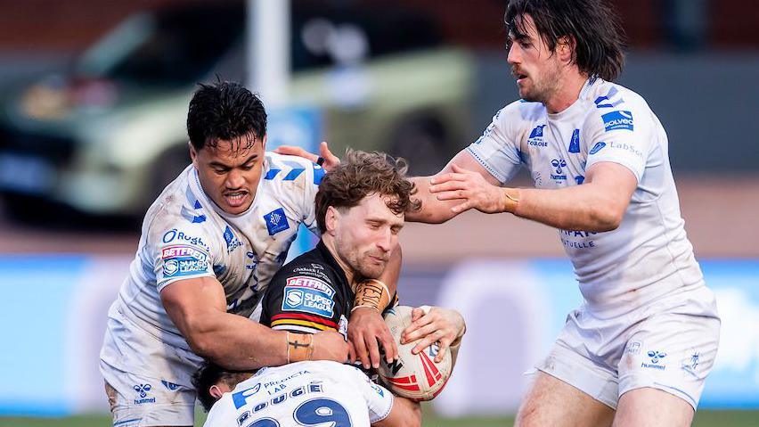 Bradford Bulls player Ethan Ryan is tackled by three Toulouse players.