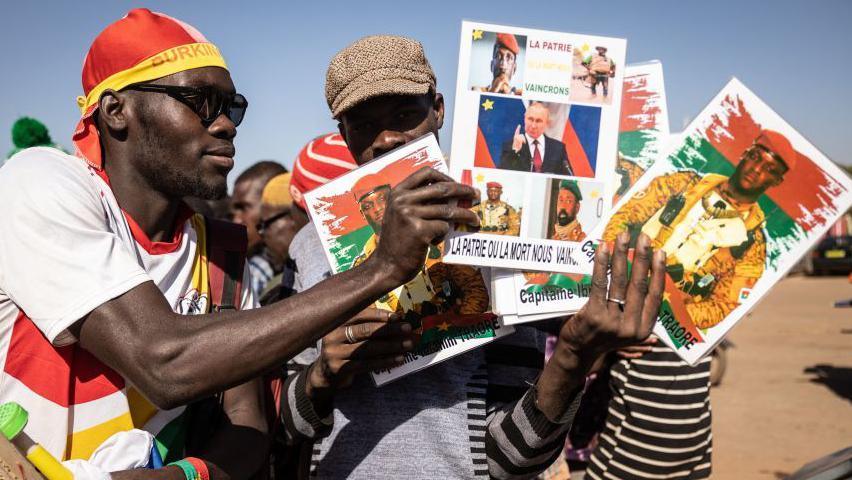 Men hold photos of Burkina Faso President Captain Ibrahim Traoré, Russian President Vladimir Putin and other military leaders during a protest to support the Burkina Faso leader and to demand the departure of France's ambassador and military forces, in Ouagadougou - 20 January 2023.