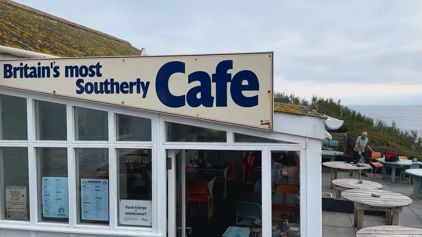 Cafe overlooking sea man stacking chairs 