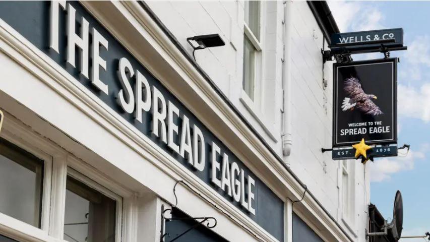 The exterior of a local pub displaying a sign which reads 'The Spread Eagle' in white lettering against a black background