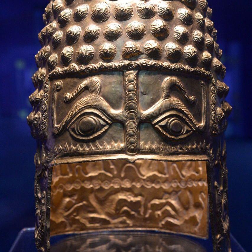 A strikingly decorated ancient golden helmet, with eyes an snakes