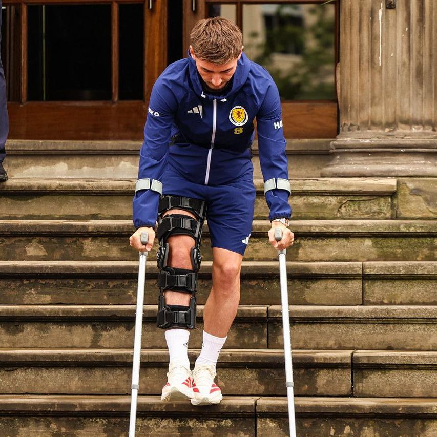 Billy Gilmour leaves the team hotel on crutches after sustaining a knee injury