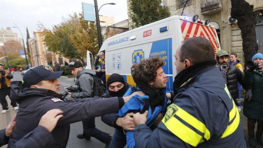 Police and special forces grab a protester as they move in to clear tents from a protest in Tbilisi in Georgia