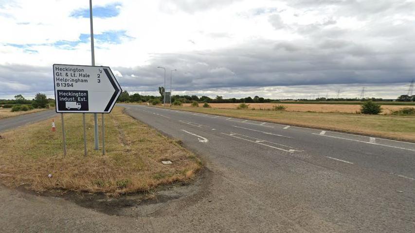 A long straight section of the A17, with a sign on the central reservation pointing towards Heckington