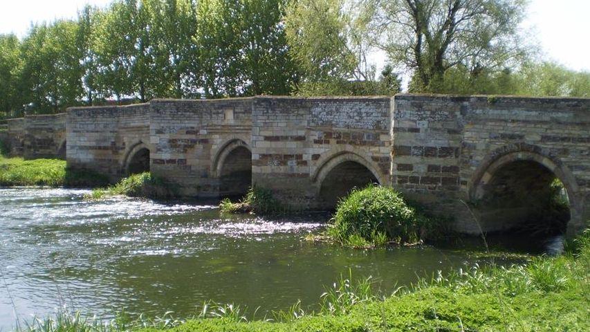 A river flows under a bridge with four arches