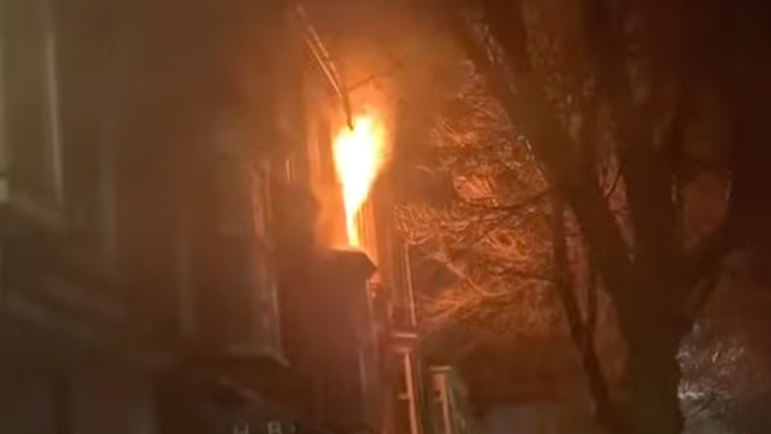 A blurred image of a fire on a top floor flat in Paignton. Flames can be seen coming out of a window in the picture, which is taken at night