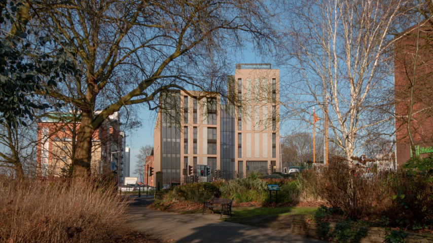 A seven-storey block of student flats on a main road in Leicester seen from an adjacent park