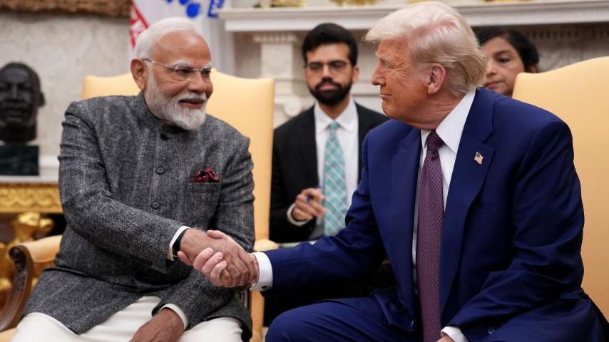 US President Donald Trump, seen on the right, wearing a dark blue site with purple tie, shaking hands with Indian Prime Minister Narendra Modi, seen on the left wearing a grey suit with a Nehru collar, at a meeting in the Oval Office at the White House on 13 February 2025 