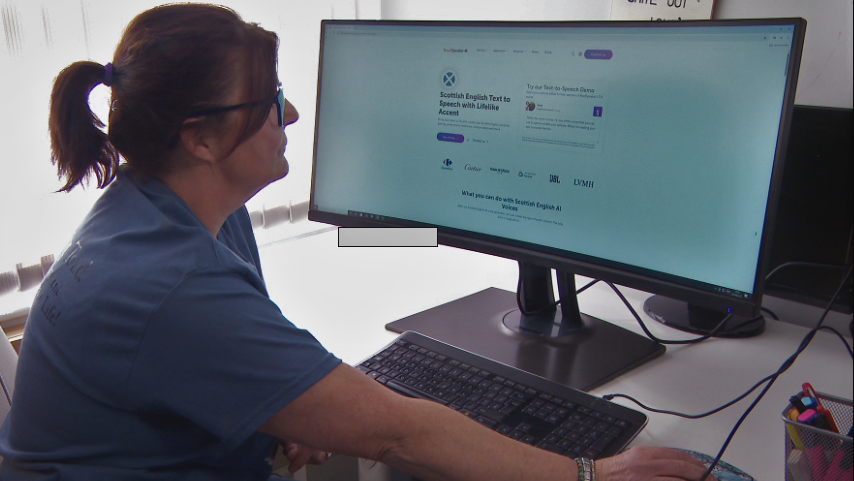 Gayanne is sat at her desk, staring at a computer screen which has the ReadSpeaker website opened. It says "Scottish English Text to Speech with Lifelike Accent".