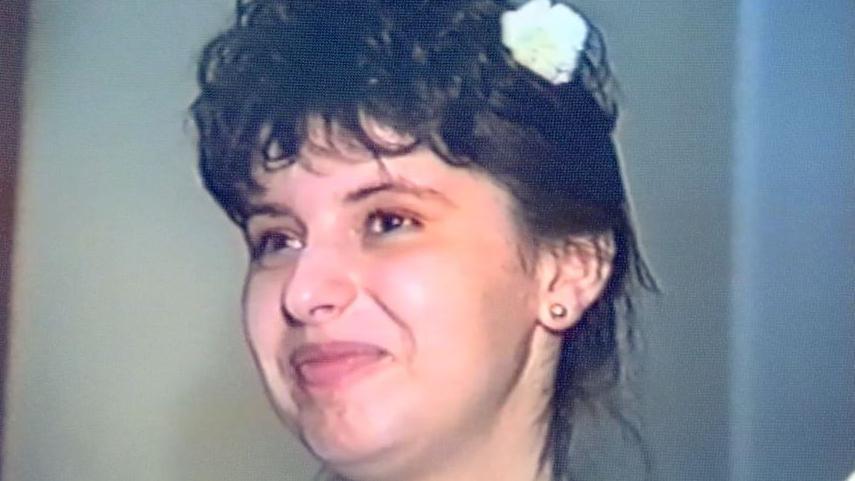 Monika on her wedding day in a white gown with a white flower in her hair