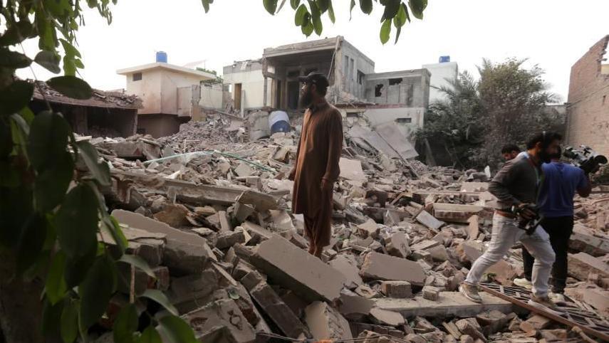 A man standing on the rubble of a building in Muridke 