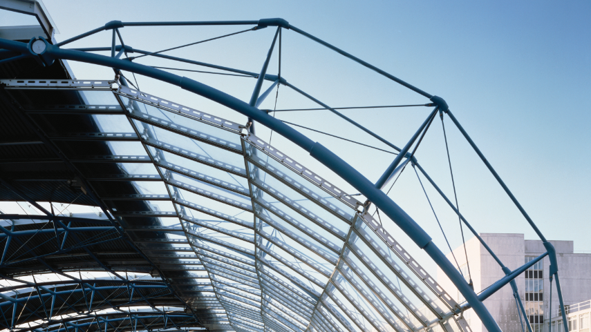 A large glass-and-steel International Terminal at Waterloo. The structure is curved. The sky is blue.