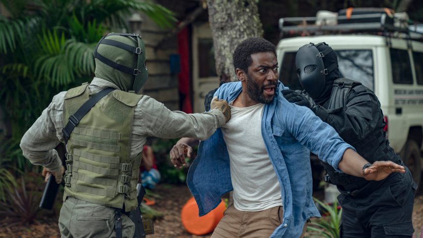 Ashley Thomas looking scared as two masked men push him