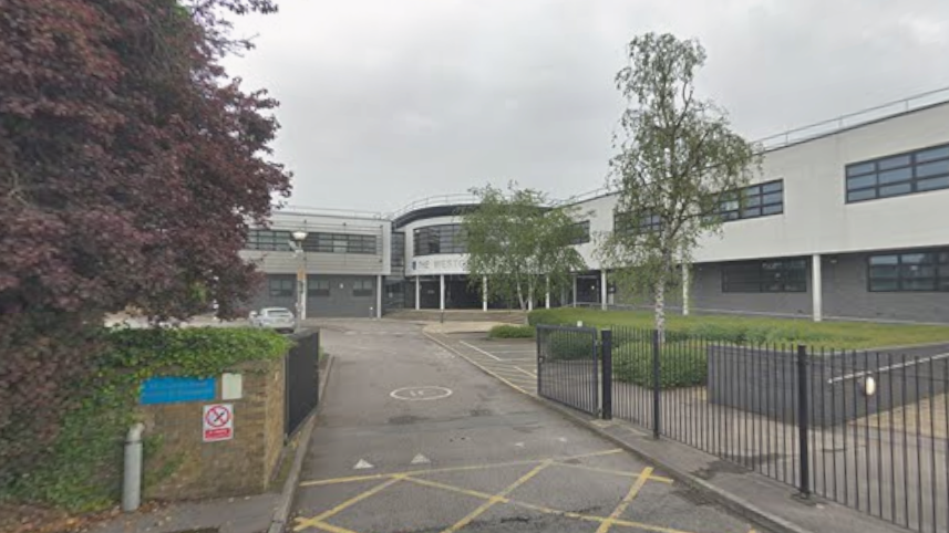 A general view picture of the school, a two-storey building with black gates surrounding it.