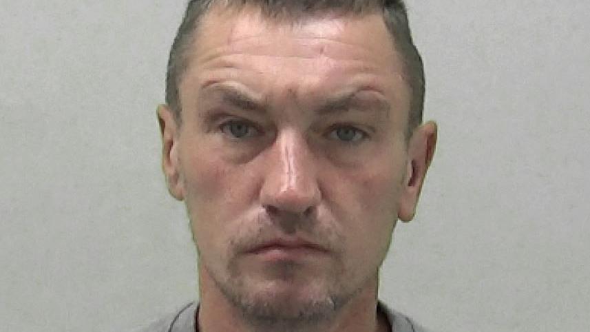 Mugshot of a man with stubble and short dark hair