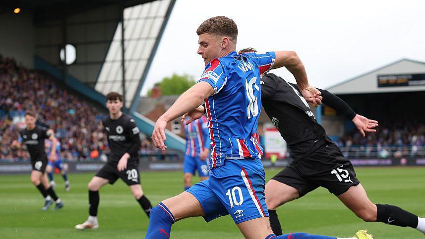 Regan Linney attacking for Carlisle while being pursued by Boreham Wood's (no 15) James Clarke