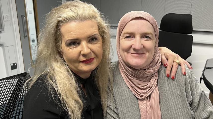 Tatiana Qureshi (left) has an arm around Julie Siddiqui (right) in a radio studio