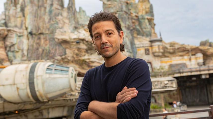 Diego Luna standing with his arms crossed in front of a space ship on set