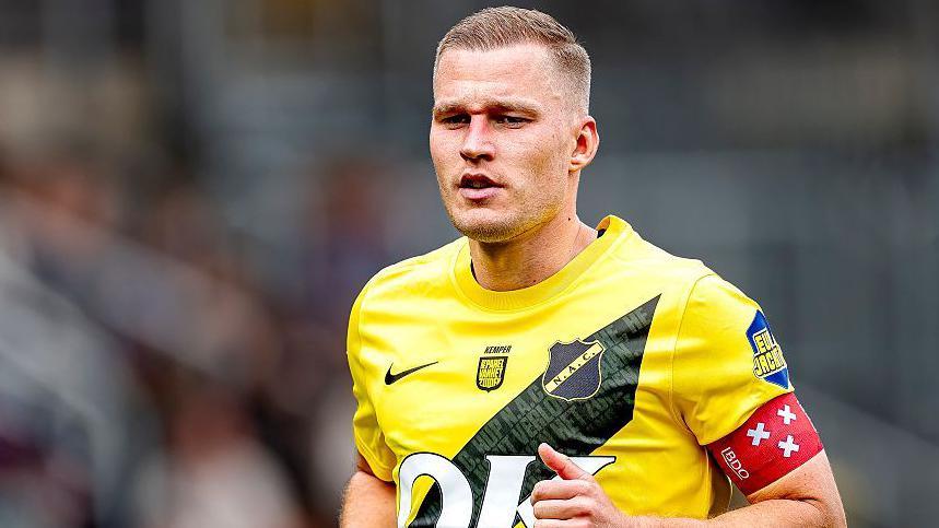 Boy Kemper in action for NAC Breda wearing a yellow playing shirt with a black diagonal line running from his left shoulder