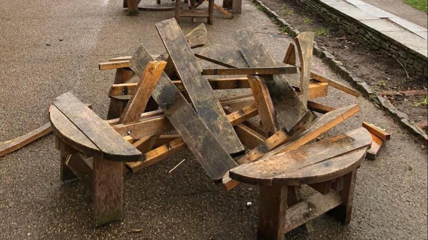 A broken four-seater picnic bench. The table has been completely destroyed.