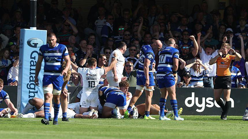 Josh Bayliss (left) walks with his head down as Exeter players in the background celebrate and the referee (right) holds the whistle to his mouth