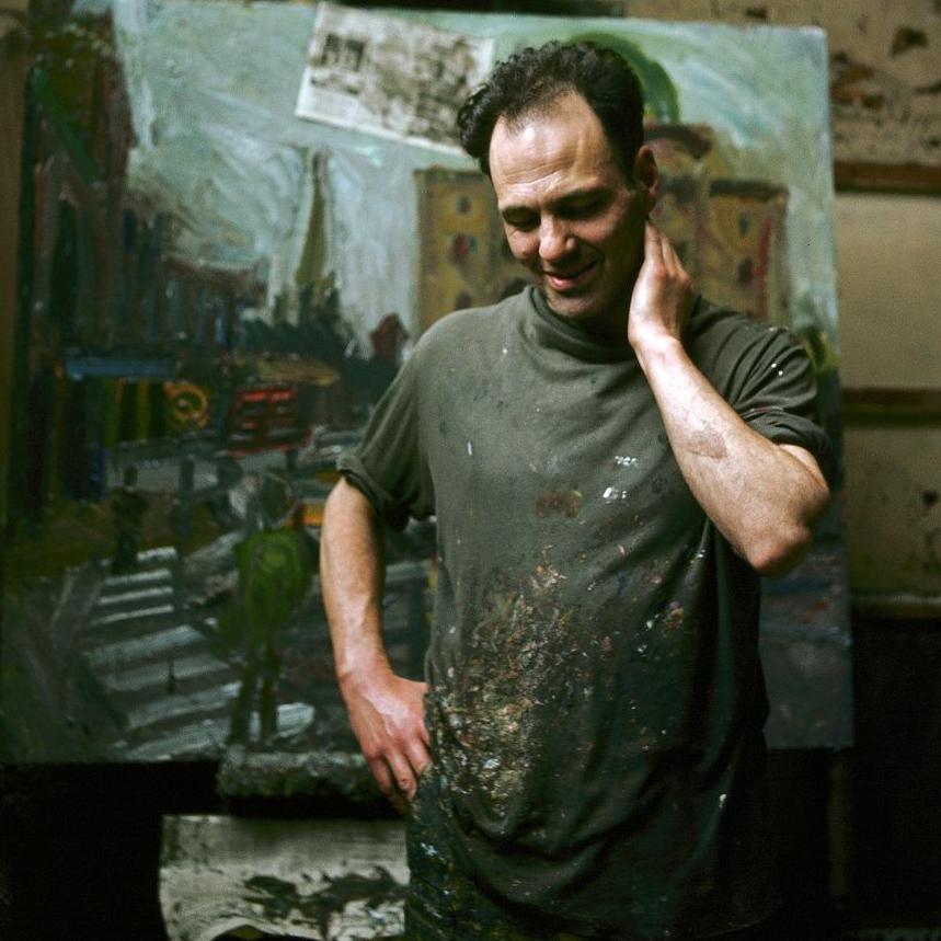 Frank Auerbach is pictured at work in his studio, in a paint-stained apron with a scene from a street with steps behind him