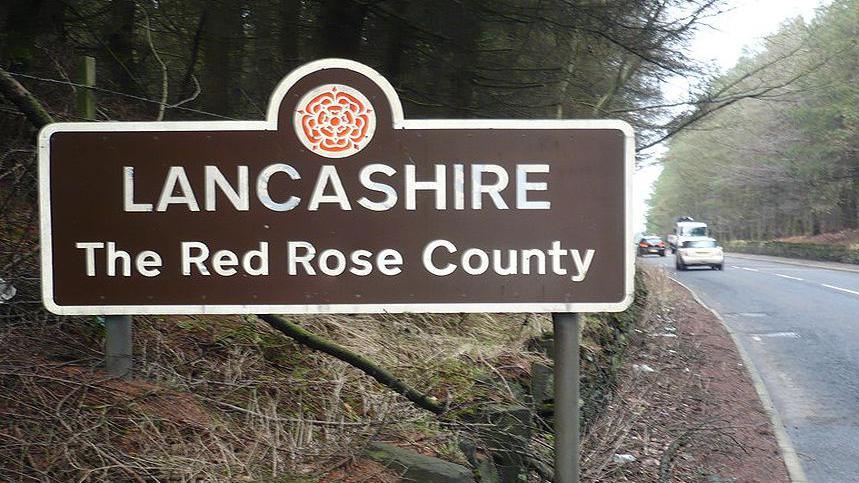 Sign saying Lancashire The Red Rose County at the side of a road.