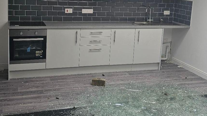 Broken glass and brick on floor of Ramsgate kitchen flat