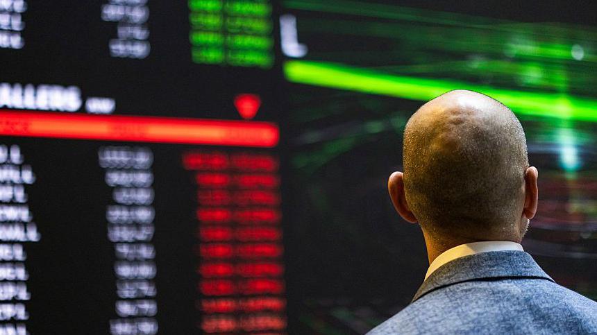 A trader on a trading floor looking at stock prices rising and falling