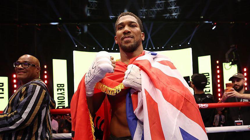 Anthony Joshua celebrates with the Union Jack draped over him