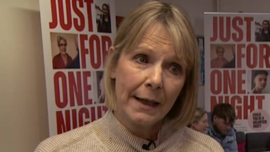 A woman with bobbed hair tilts her head towards the camera. Behind her are signs for the charity saying "just for one night".