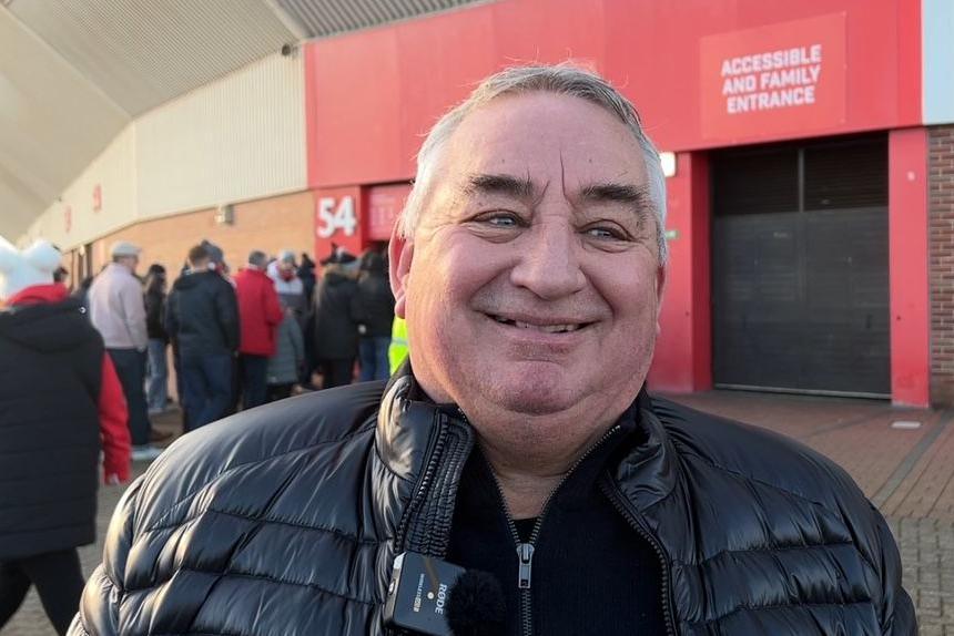 Ian Smith, outside the Stadium of Light in Sunderland. He has short grey hair and is wearing a black puffer jacket. He is smiling with a broad grin.