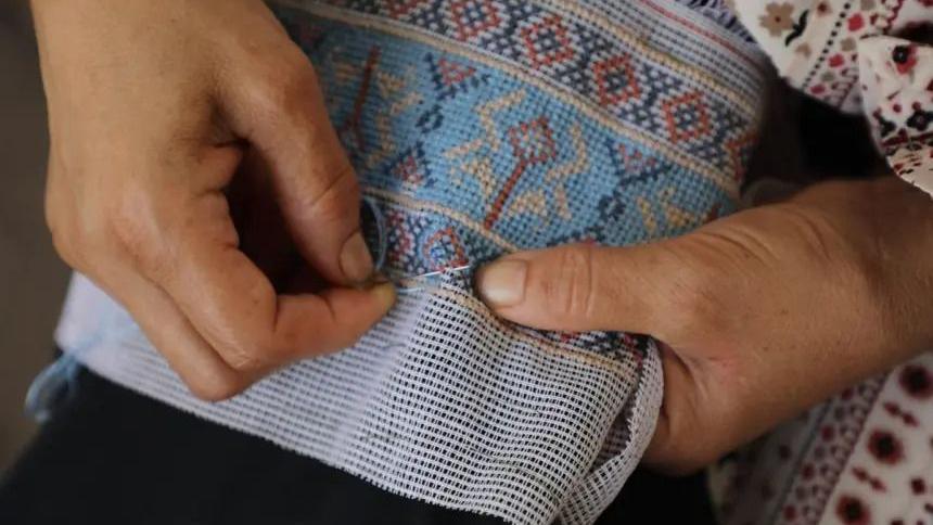 A woman sows a decorative item.