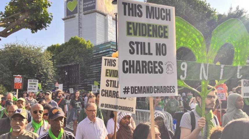 Grenfell campaigners carrying placards and signs march through west London