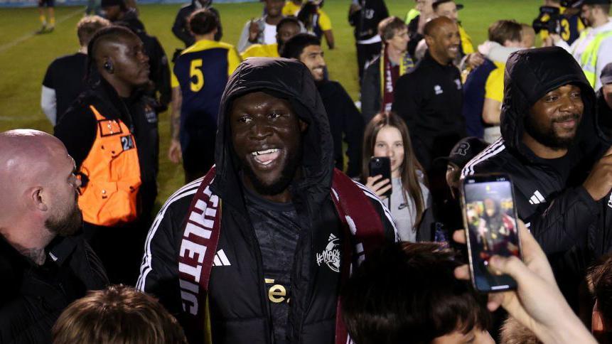 Stormzy celebrates promotion with AFC Croydon Athletic players after the Combined Counties Premier League South play-off final in 2024