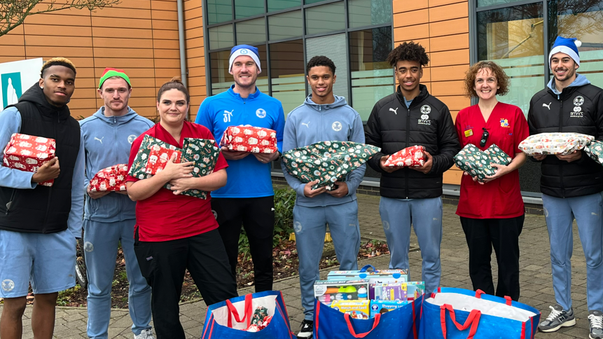 Peterborough United players and hospital staff holding presents outside the hospital. 