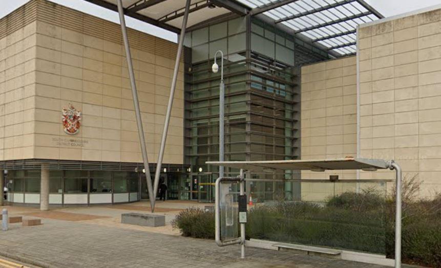 Beige building with the word South Cambridgeshire District Council on the front. Two metal beams in a v shape are in front with glass frontage in the middle.